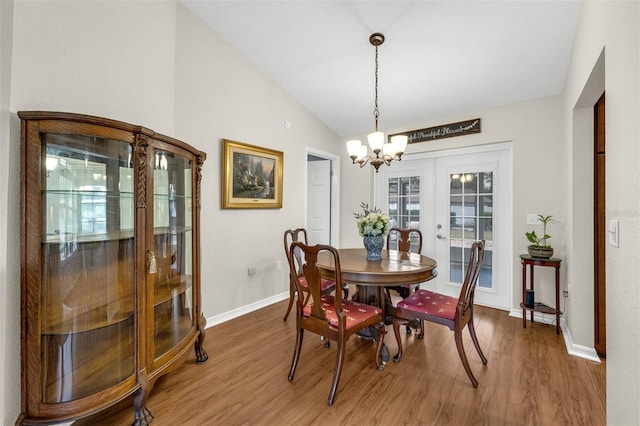 dining space featuring light wood-style flooring, baseboards, vaulted ceiling, french doors, and a chandelier