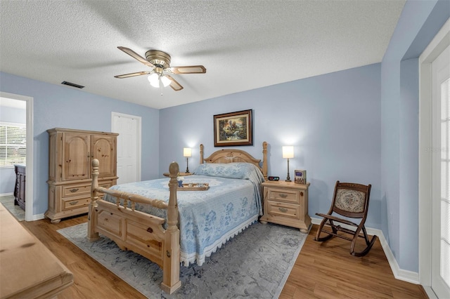 bedroom with light wood finished floors, baseboards, a textured ceiling, and ceiling fan