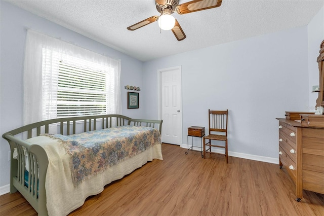 bedroom with wood finished floors, baseboards, a textured ceiling, and a ceiling fan