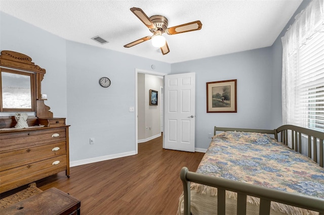 bedroom featuring dark wood-style floors, baseboards, ceiling fan, and a textured ceiling
