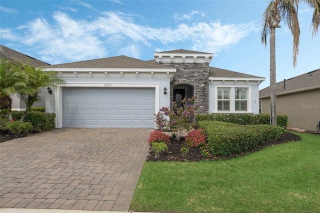 1027 Timbervale Trl, Clermont, FL 34715 - view of front of property featuring decorative driveway, an attached garage, stucco siding, a front yard, and stone siding