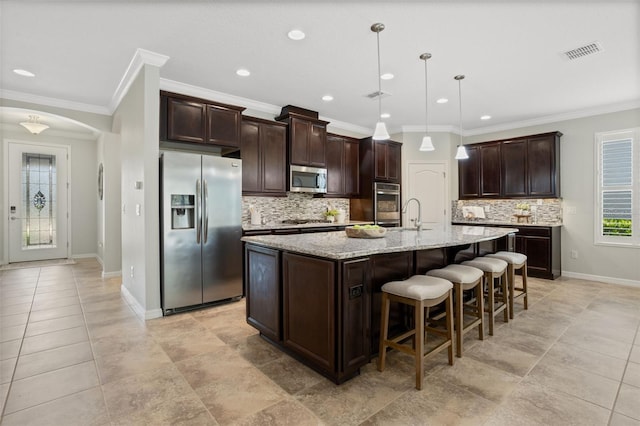 1027 Timbervale Trl, Clermont, FL 34715 - kitchen featuring appliances with stainless steel finishes, decorative backsplash, an island with sink, a breakfast bar, and dark brown cabinets