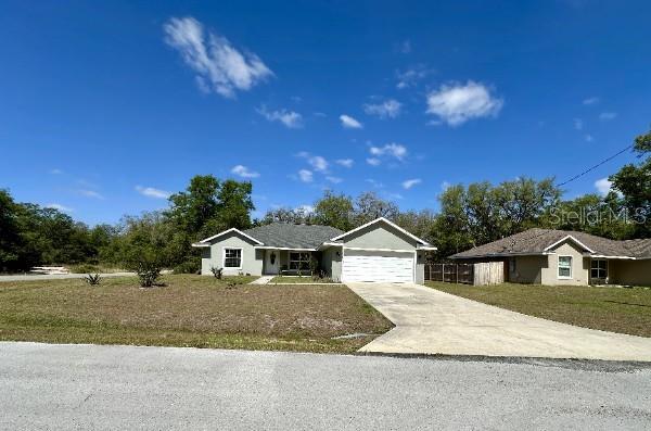 ranch-style home with concrete driveway, a garage, and a front lawn