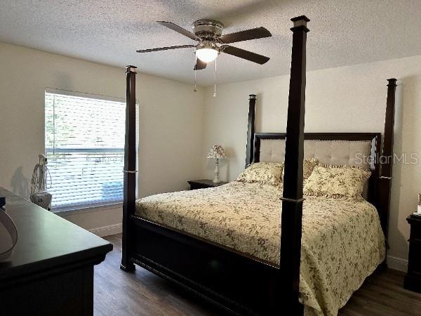 bedroom featuring dark wood finished floors, baseboards, a textured ceiling, and ceiling fan
