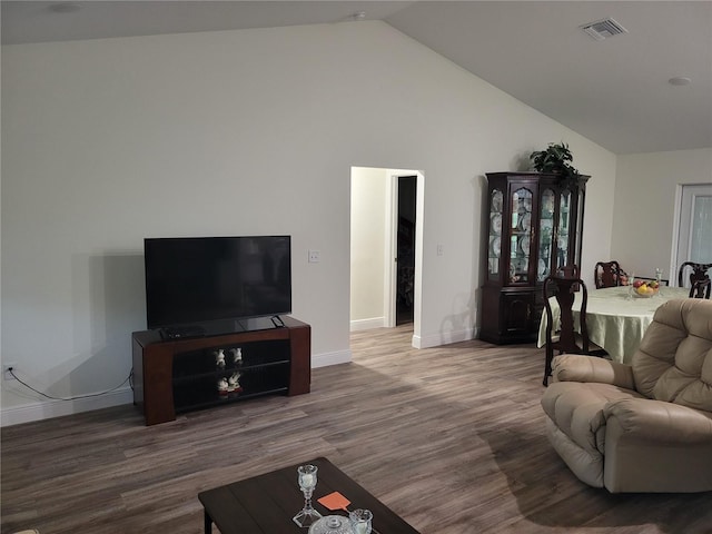 living room featuring wood finished floors, baseboards, and high vaulted ceiling