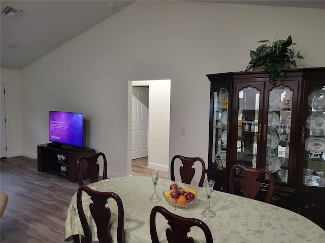 dining space with wood finished floors, baseboards, and high vaulted ceiling