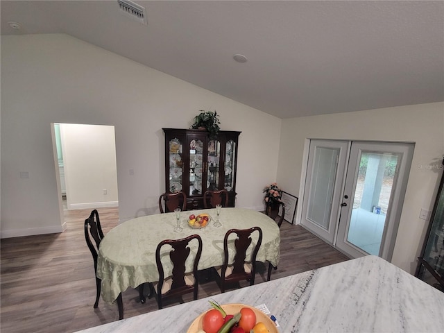dining space featuring vaulted ceiling, wood finished floors, baseboards, and french doors