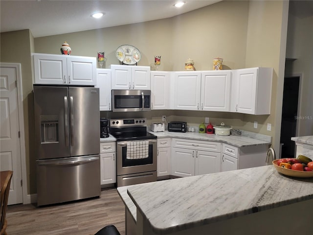 kitchen with stainless steel appliances, white cabinets, lofted ceiling, wood finished floors, and recessed lighting