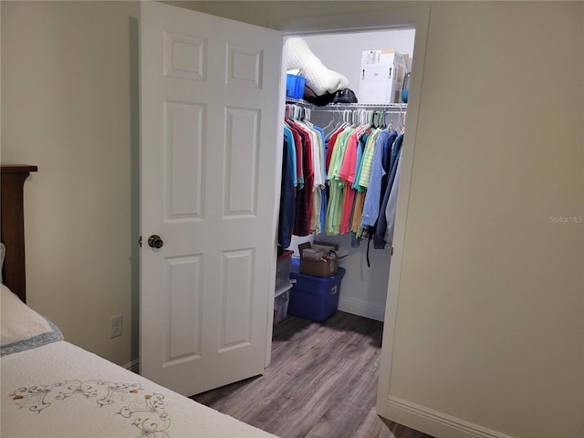 bedroom featuring wood finished floors, a closet, baseboards, and a walk in closet