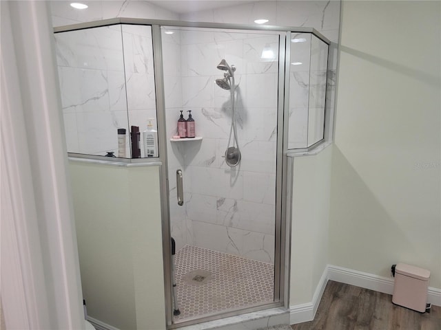 full bathroom with a shower stall, baseboards, and wood finished floors