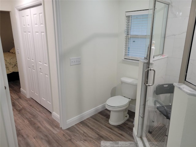 full bath featuring wood finished floors, a shower stall, baseboards, and toilet