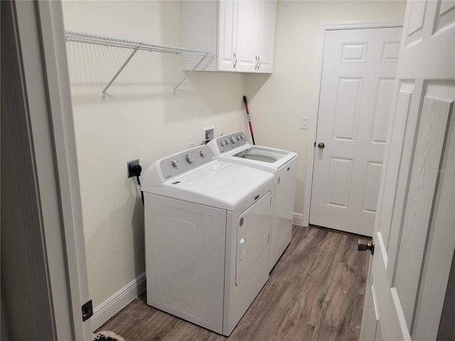 laundry area with cabinet space, washing machine and clothes dryer, wood finished floors, and baseboards