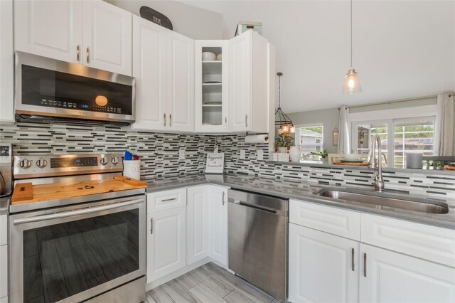 12401 Blue Heron Way, Leesburg, FL 34788 - kitchen featuring appliances with stainless steel finishes, a sink, decorative backsplash, glass insert cabinets, and white cabinets