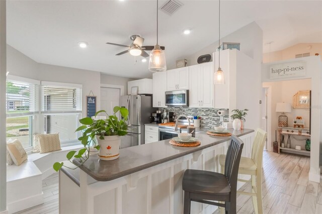 12401 Blue Heron Way, Leesburg, FL 34788 - kitchen featuring stainless steel appliances, vaulted ceiling, decorative backsplash, a breakfast bar area, and ceiling fan