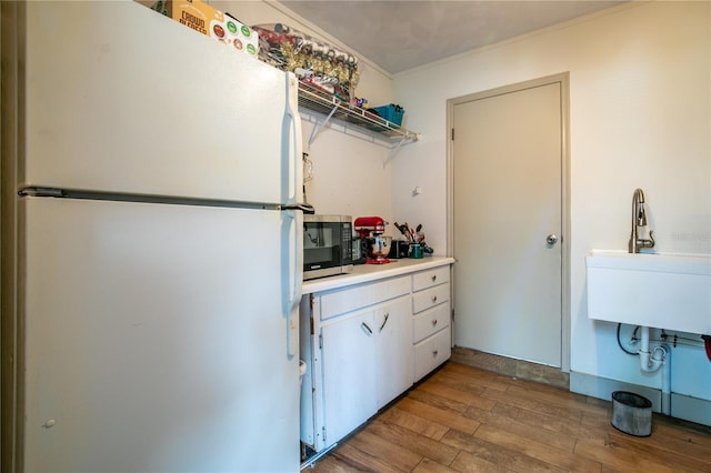 800 Jefferis Ct, Eustis, FL 32726 - kitchen with freestanding refrigerator, stainless steel microwave, wood finished floors, ornamental molding, and light countertops