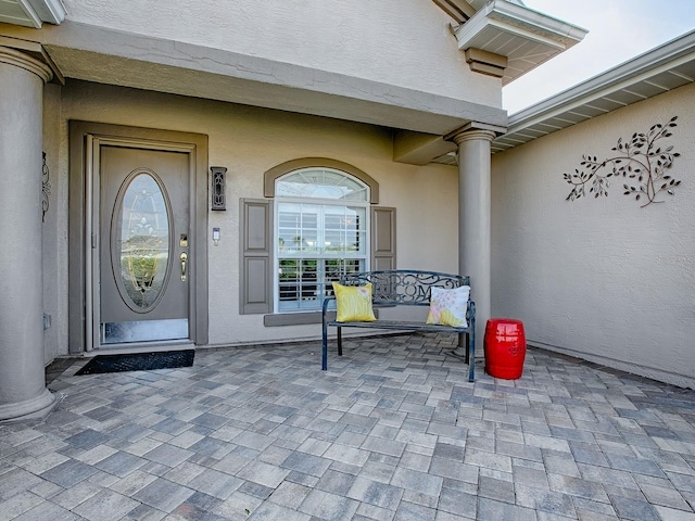 view of exterior entry with stucco siding and covered porch