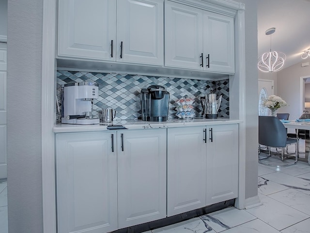 bar featuring light marble finish flooring, decorative backsplash, and a chandelier