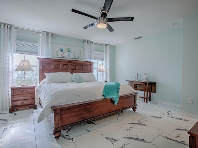 bedroom with multiple windows, light marble finish floors, ceiling fan, and baseboards