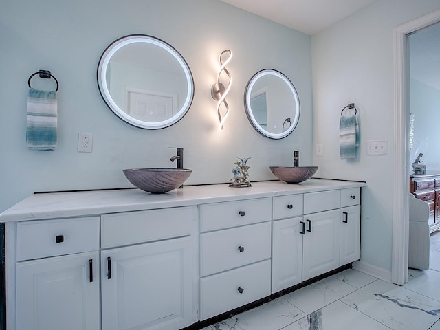 bathroom featuring marble look tiles, double vanity, and baseboards