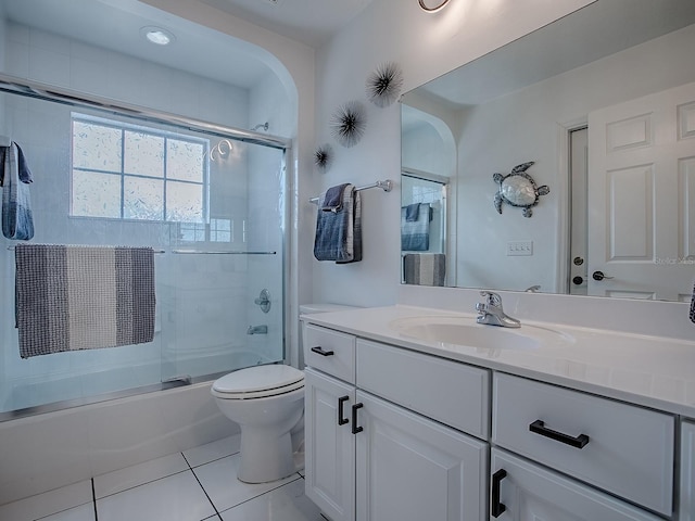 full bath with tile patterned floors, toilet, vanity, and bath / shower combo with glass door