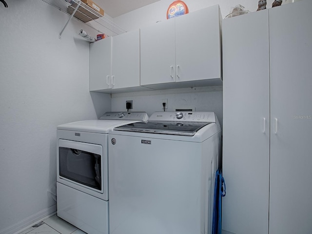 washroom featuring separate washer and dryer, cabinet space, light marble finish flooring, and baseboards