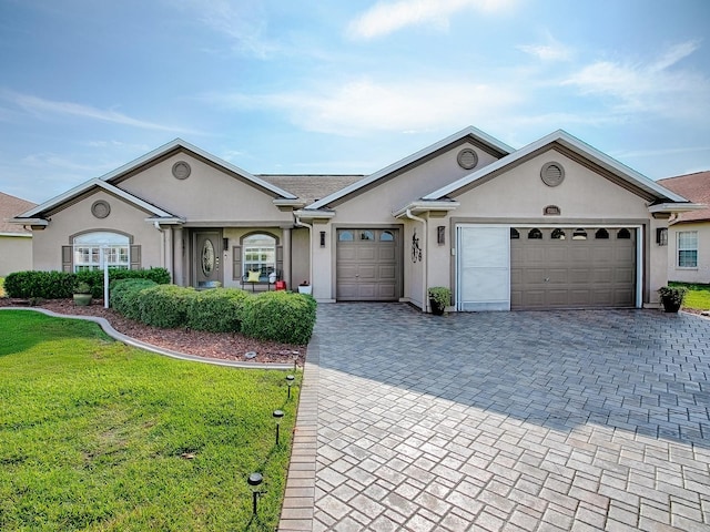 ranch-style home featuring stucco siding, a front yard, decorative driveway, and an attached garage