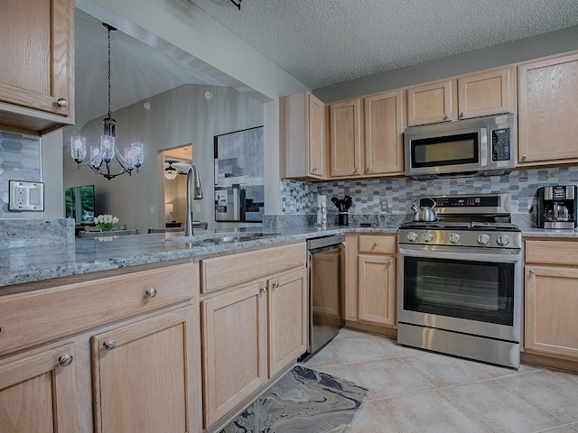 kitchen featuring appliances with stainless steel finishes, light brown cabinetry, a sink, a chandelier, and backsplash