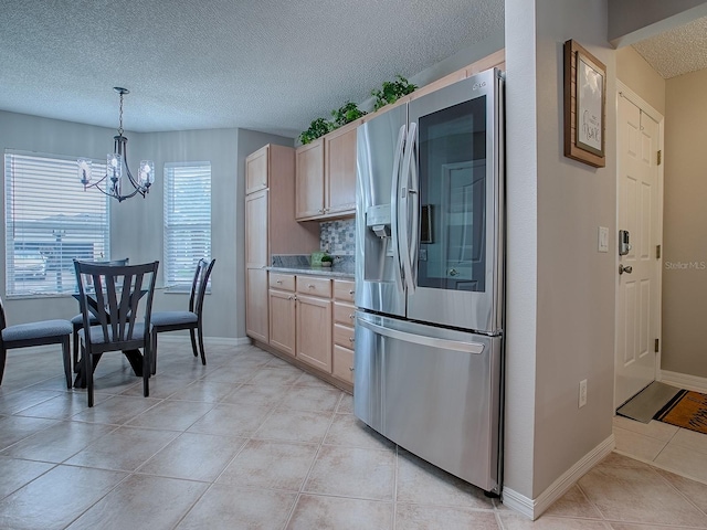 kitchen featuring stainless steel refrigerator with ice dispenser, a textured ceiling, a chandelier, light tile patterned floors, and light brown cabinetry