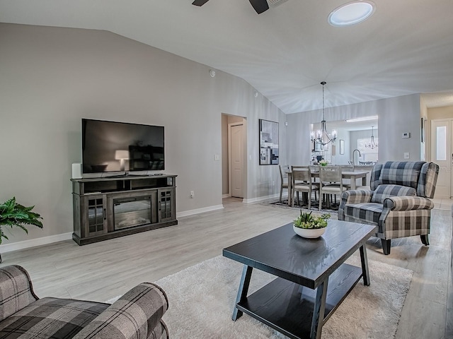 living area featuring lofted ceiling, a chandelier, light wood finished floors, ceiling fan, and baseboards