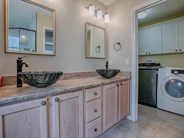 full bath featuring washing machine and dryer, tile patterned flooring, double vanity, and an enclosed shower