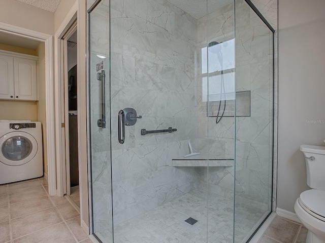 bathroom with washer / clothes dryer, toilet, a stall shower, tile patterned flooring, and a textured ceiling