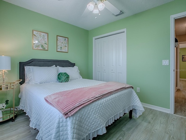 bedroom with a closet, wood finished floors, baseboards, and ceiling fan