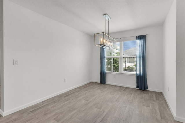 3745 Causey Ct, The Villages, FL 32163 - unfurnished room with a chandelier, light wood finished floors, and baseboards
