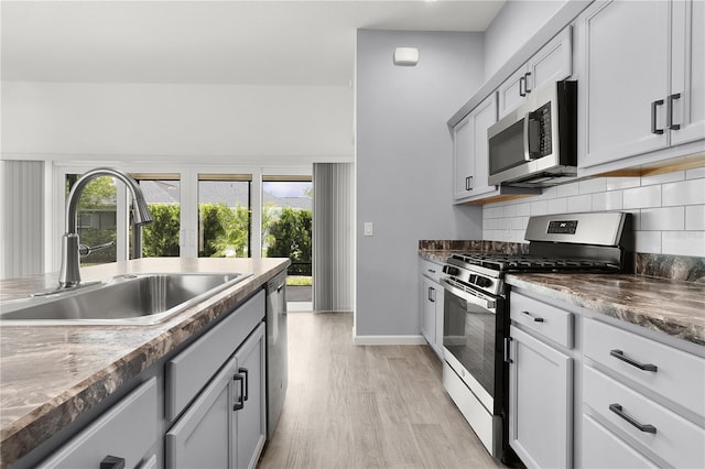 3745 Causey Ct, The Villages, FL 32163 - kitchen with appliances with stainless steel finishes, a sink, light wood-style floors, backsplash, and baseboards