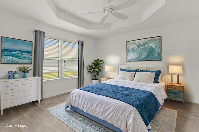 3745 Causey Ct, The Villages, FL 32163 - bedroom featuring a tray ceiling, baseboards, wood finished floors, and ceiling fan