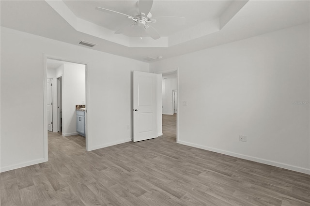 3745 Causey Ct, The Villages, FL 32163 - unfurnished bedroom featuring a tray ceiling, light wood-style flooring, and baseboards