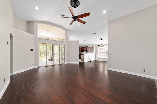 6259 SE 120th Pl, Belleview, FL 34420 - unfurnished living room featuring a ceiling fan, plenty of natural light, a chandelier, vaulted ceiling, and dark wood-style floors