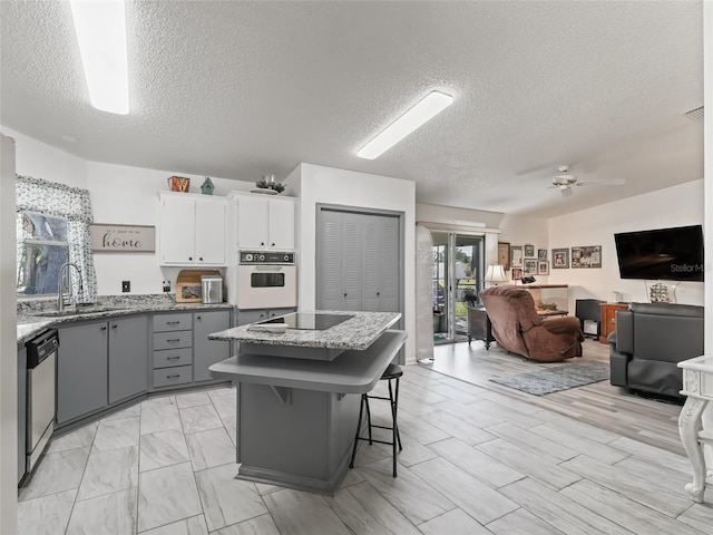 1202 Del Toro Dr, Lady Lake, FL 32159 - kitchen featuring white oven, a sink, stainless steel dishwasher, gray cabinets, and a textured ceiling
