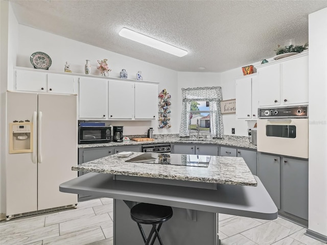 1202 Del Toro Dr, Lady Lake, FL 32159 - kitchen featuring black appliances, a sink, white cabinetry, a breakfast bar area, and light stone countertops