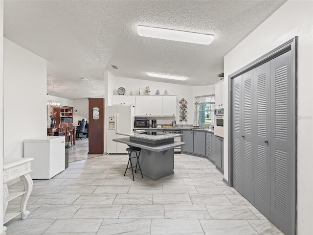 1202 Del Toro Dr, Lady Lake, FL 32159 - kitchen with white appliances, a textured ceiling, a center island, a breakfast bar, and light countertops