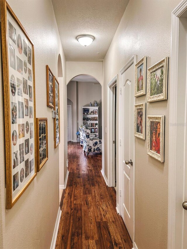 33818 Venice Ln, Sorrento, FL 32776 - hallway with arched walkways, wood finished floors, a textured ceiling, and baseboards