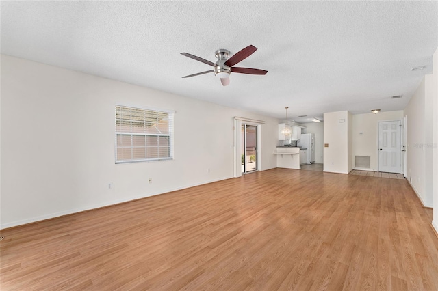 403 Duarte Ln, The Villages, FL 32159 - unfurnished living room featuring a ceiling fan, light wood-style flooring, a textured ceiling, and baseboards