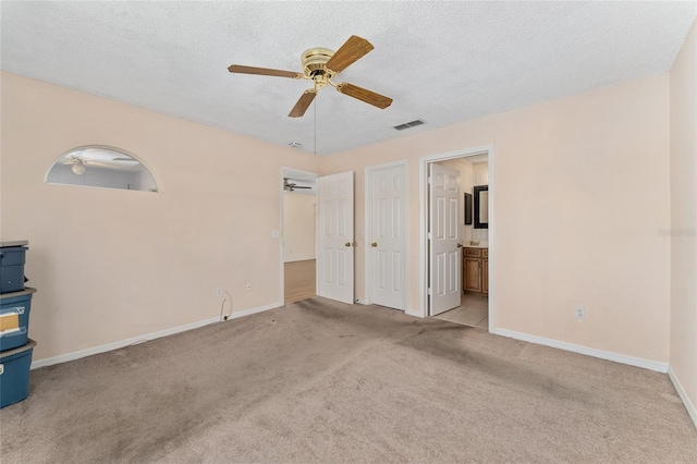 403 Duarte Ln, The Villages, FL 32159 - unfurnished bedroom with carpet floors, baseboards, ensuite bath, a ceiling fan, and a textured ceiling