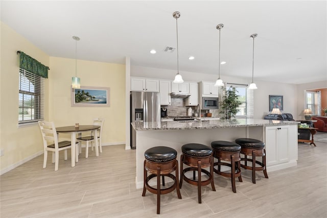 503 Vigo St, Davenport, FL 33837 - kitchen with stainless steel appliances, white cabinetry, a large island with sink, a breakfast bar area, and baseboards