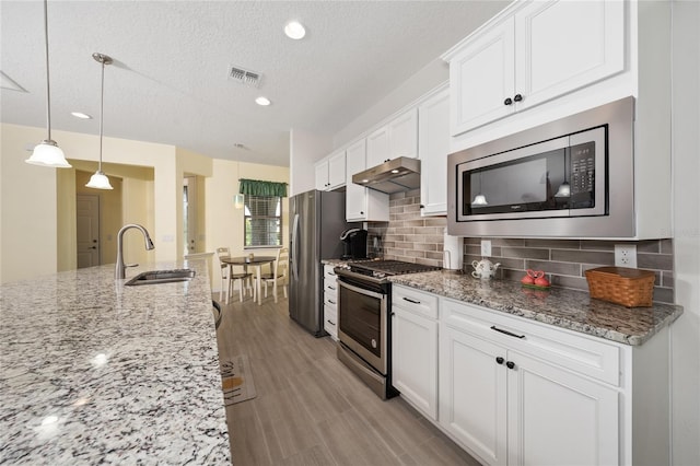 503 Vigo St, Davenport, FL 33837 - kitchen featuring appliances with stainless steel finishes, a sink, white cabinets, backsplash, and a textured ceiling