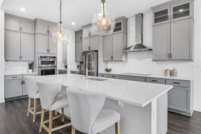 14513 Winter Stay Dr, Winter Garden, FL 34787 - kitchen featuring gray cabinetry, wall chimney exhaust hood, stainless steel appliances, tasteful backsplash, and dark wood-type flooring