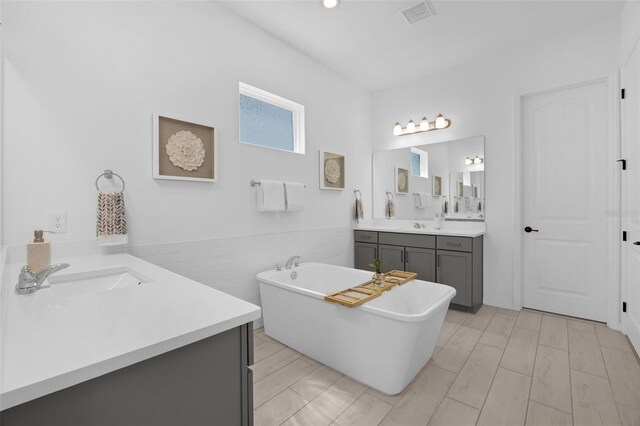 14513 Winter Stay Dr, Winter Garden, FL 34787 - full bath with two vanities, a soaking tub, tile walls, and a wainscoted wall
