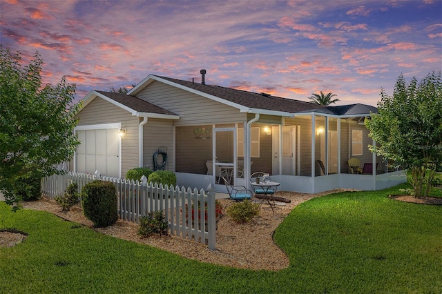 back of property with a sunroom, a garage, and roof with shingles