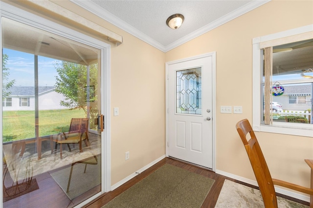 foyer with dark wood-style floors, ornamental molding, baseboards, and a textured ceiling