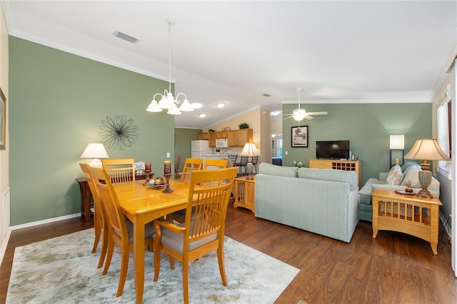 dining area featuring ornamental molding, dark wood-style flooring, a chandelier, vaulted ceiling, and a ceiling fan